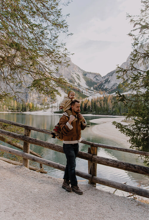 A father carrying his child beside a mountain lake